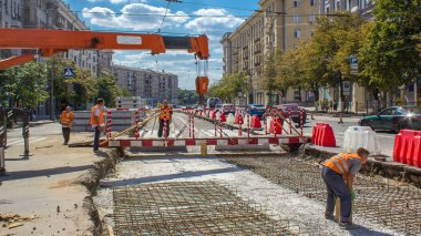 Orange construction telescopic mobile crane moving small pedestrian bridge timelapse. Industrial workers with hardhats and uniform. Reconstruction of tram tracks in the city street clipart