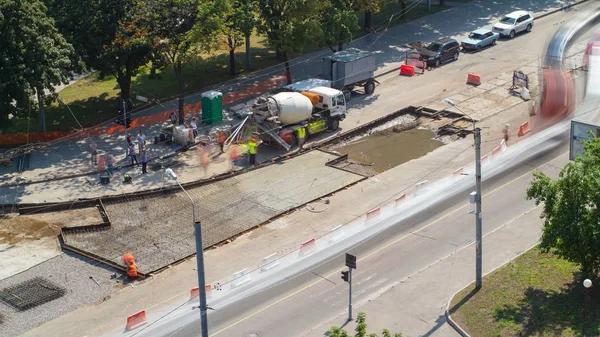 Concrete works for road maintenance construction with many workers and mixer timelapse. Aerial top view. Reconstruction of tram tracks