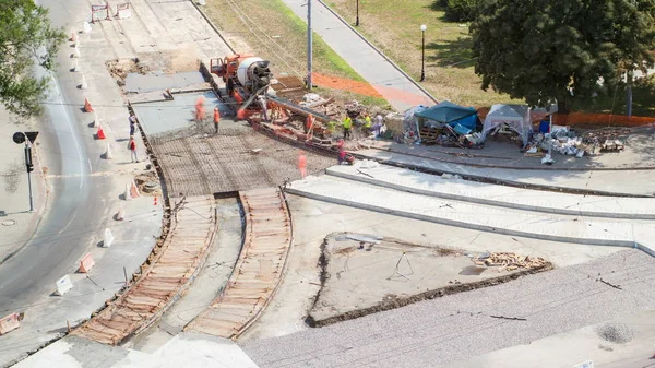 Concrete works for road maintenance construction with many workers and mixer timelapse. Aerial top view. Reconstruction of tram tracks on intersection