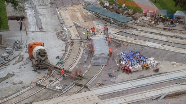 Concrete works for road maintenance construction with many workers and mixer timelapse. Aerial top view. Reconstruction of tram tracks on intersection