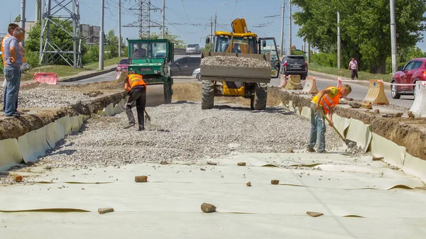 Work bulldozer on the construction of a road timelapse. Crushed stone on substrate. Support activities and road under construction. Reconstruction of tram tracks