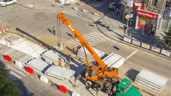 道路建設サイト タイムラプスでクレーン コンクリート板をインストールします Hardhats と制服産業労働者 空中の平面図です トラムの復興を街で追跡します — ストック写真