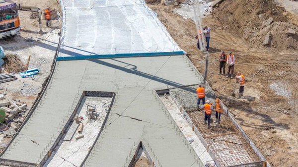 Concrete works for road construction with many workers in uniform and concrete pump machine timelapse. Reconstruction of tram tracks. Aerial top view from above