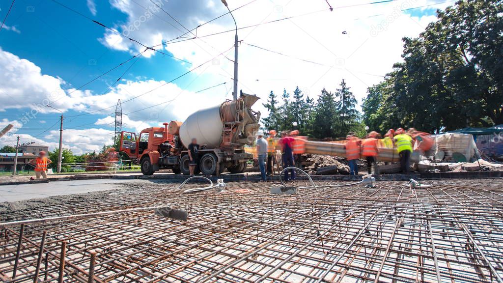 Concrete works for road construction with many workers and mixer timelapse hyperlapse. Pouring mortar to metal reinforcement. Reconstruction of tram tracks