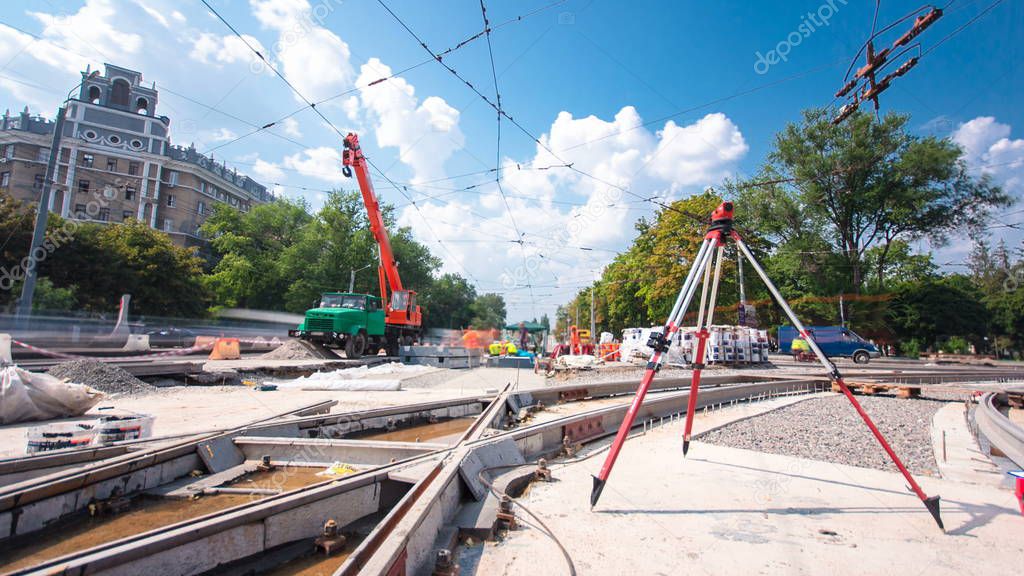 Installing concrete plates by crane at road construction site timelapse hyperlapse. Industrial workers with hardhats and uniform. Electronic level on a tripod. Reconstruction of tram tracks on intersection