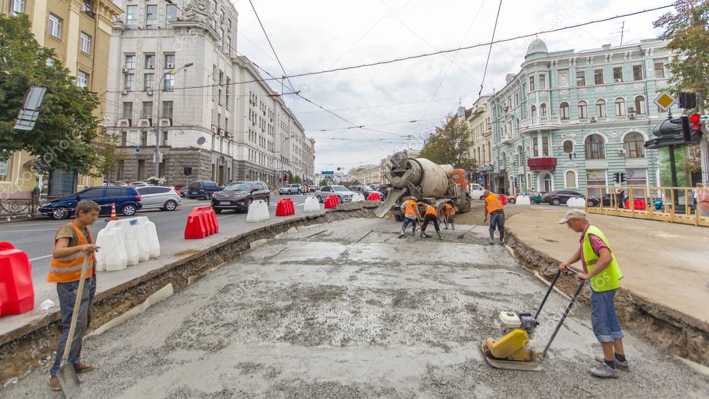 Concrete works for road construction with many workers in uniform and mixer machine timelapse. Reconstruction of tram tracks