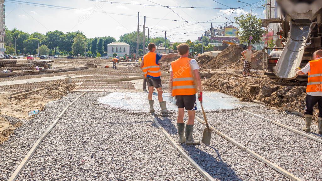 Concrete works for road construction with many workers in uniform and mixer machine timelapse. Reconstruction of tram tracks
