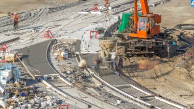 Beton yol yapımı ile üniforma ve mikser makine timelapse birçok işçi için turuncu vinç çalışır. Tramvay yeniden inşası izler. Yukarıdan hava üstten görünüm