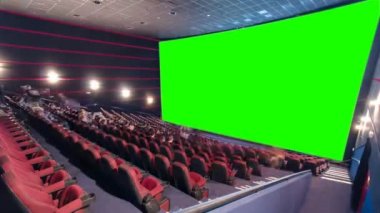 İzleyiciler, kırmızı sandalye ve yeşil projeksiyon ekran timelapse ile sinema film tiyatro konser salonu