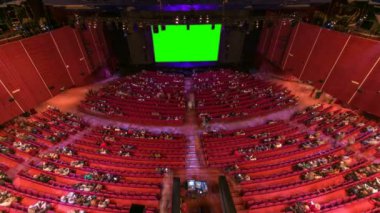 İzleyiciler, kırmızı sandalye ve yeşil projeksiyon ekran timelapse ile sinema film tiyatro konser salonu