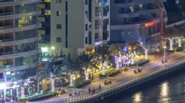 Dubai Marina havadan görünümden bir noktadan gece timelapse. Waterfront adlı mesire üzerinde yürüyen insanlar. Modern gökdelenler ve konut kuleleri parlayan pencerelerle aydınlatılmış