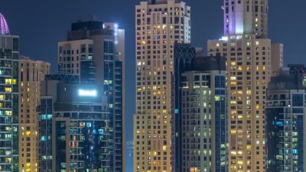 Glowing windows in multistory modern glass and metal residential buildings light up at night timelapse. — Stock Video