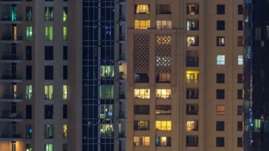 Çok öykülü modern cam ve metal kadar ışık gece timelapse bina konut içinde parlayan pencere eşiği.