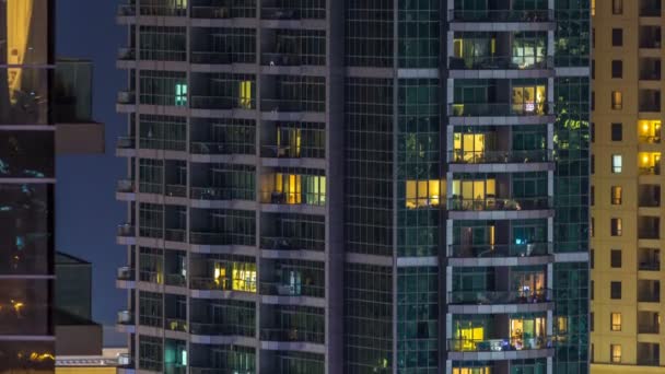 Ventanas brillantes en vidrio moderno de varios pisos y edificio residencial de metal se iluminan por la noche timelapse . — Vídeo de stock