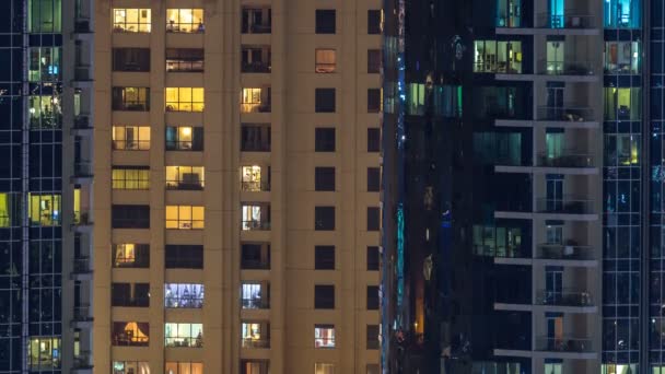 Glühende Fenster in mehrstöckigen modernen Wohngebäuden aus Glas und Metall leuchten im Zeitraffer der Nacht. — Stockvideo