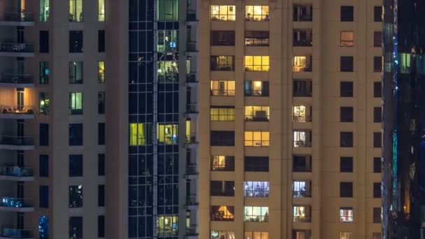 Glühende Fenster in mehrstöckigen modernen Wohngebäuden aus Glas und Metall leuchten im Zeitraffer der Nacht. — Stockvideo