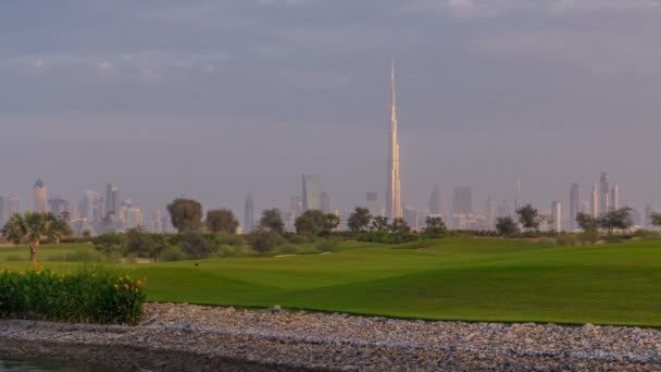 Vackra golfbana under sunrise runt moderna skyskrapor i Dubai Downtown timelapse i lyxiga Dubai city, Förenade Arabemiraten — Stockvideo