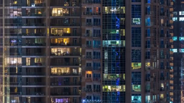 Fenêtres lumineuses dans un immeuble résidentiel en verre moderne à plusieurs étages s'illuminent la nuit timelapse . — Video