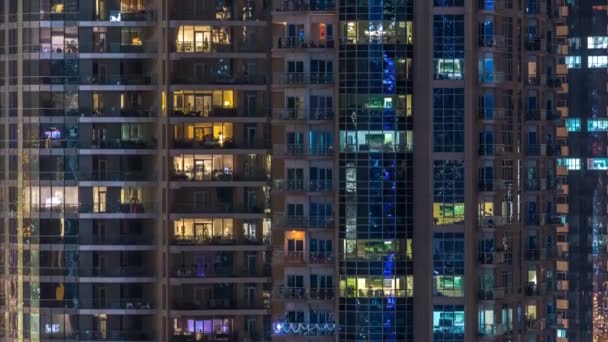 Glowing windows in multistory modern glass residential building light up at night timelapse. — Stock Video