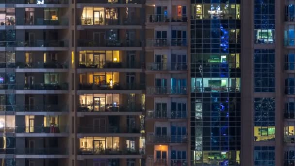 Fenêtres lumineuses dans un immeuble résidentiel en verre moderne à plusieurs étages s'illuminent la nuit timelapse . — Video