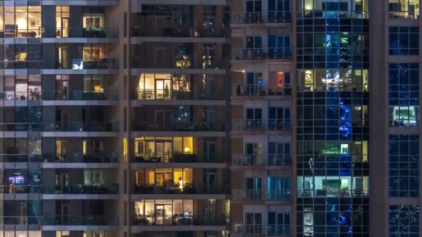 Ventanas brillantes en el edificio residencial de vidrio moderno de varios pisos se iluminan por la noche timelapse . — Vídeos de Stock