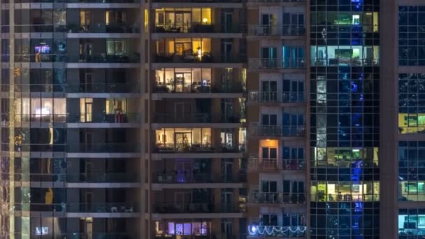 Ventanas brillantes en el edificio residencial de vidrio moderno de varios pisos se iluminan por la noche timelapse . — Vídeo de stock