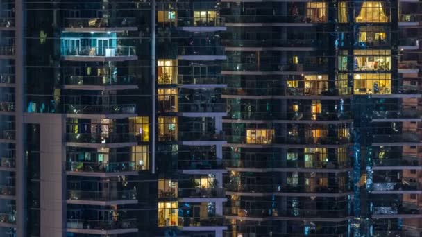 Glowing windows in multistory modern glass residential building light up at night timelapse. — Stock Video