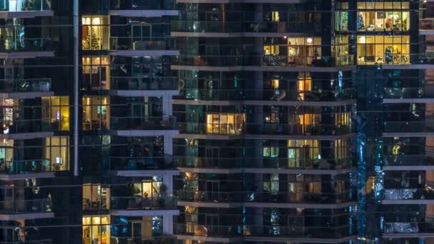 Ventanas brillantes en el edificio residencial de vidrio moderno de varios pisos se iluminan por la noche timelapse . — Vídeos de Stock