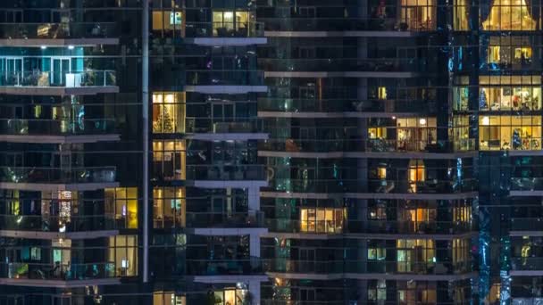 Ventanas brillantes en el edificio residencial de vidrio moderno de varios pisos se iluminan por la noche timelapse . — Vídeos de Stock