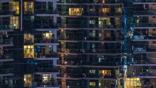 Ventanas brillantes en el edificio residencial de vidrio moderno de varios pisos se iluminan por la noche timelapse . — Vídeos de Stock