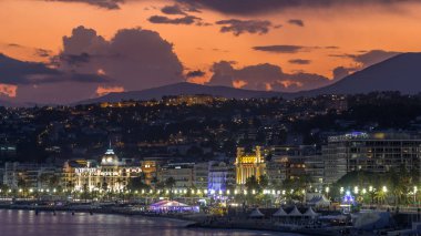 Waterfront güzel şehir ve Akdeniz deniz gün gece geçiş timelapse için. Bay of Angels yansıması su, Cote d'Azur, French Riviera, Fransa ile gezinti dramatik gökyüzü ile