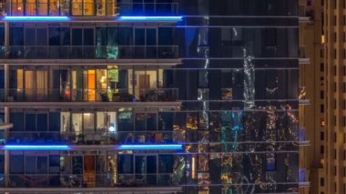 Çok öykülü modern cam ve metal kadar ışık gece timelapse bina konut içinde parlayan pencere eşiği.