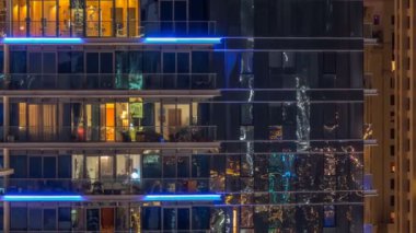 Çok öykülü modern cam ve metal kadar ışık gece timelapse bina konut içinde parlayan pencere eşiği.
