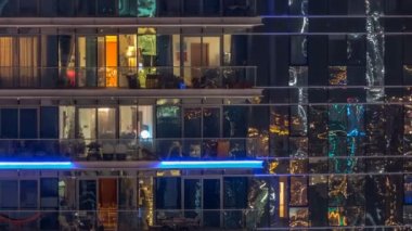 Çok öykülü modern cam ve metal kadar ışık gece timelapse bina konut içinde parlayan pencere eşiği.
