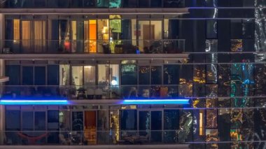 Çok öykülü modern cam ve metal kadar ışık gece timelapse bina konut içinde parlayan pencere eşiği.