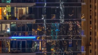 Çok öykülü modern cam ve metal kadar ışık gece timelapse bina konut içinde parlayan pencere eşiği.