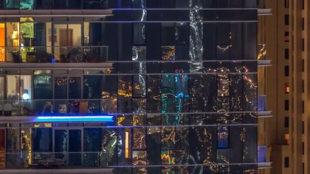 Glowing windows in multistory modern glass and metal residential building light up at night timelapse. — Stock Video
