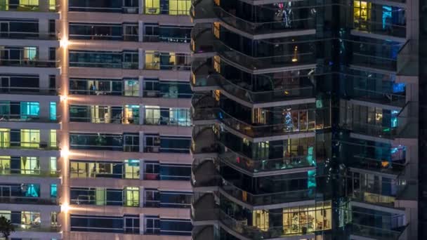 Glowing windows in multistory modern glass and metal residential building light up at night timelapse. — Stock Video