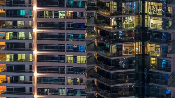 Glühende Fenster in mehrstöckigen modernen Wohngebäuden aus Glas und Metall leuchten im Zeitraffer der Nacht. — Stockvideo