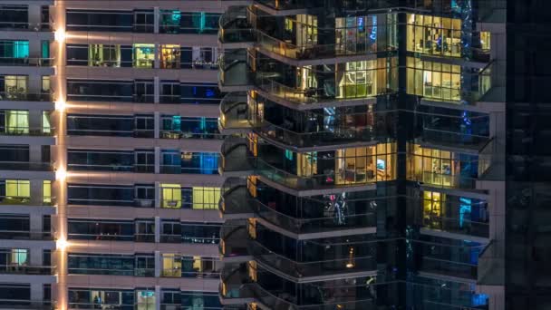 Ventanas brillantes en vidrio moderno de varios pisos y edificio residencial de metal se iluminan por la noche timelapse . — Vídeo de stock