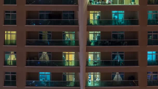 Ventanas brillantes en el edificio residencial de vidrio moderno de varios pisos se iluminan por la noche timelapse . — Vídeo de stock