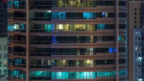 Ventanas brillantes en el edificio residencial de vidrio moderno de varios pisos se iluminan por la noche timelapse . — Vídeo de stock