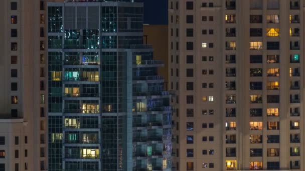 Glowing windows in multistory modern glass residential building light up at night timelapse. — Stock Video