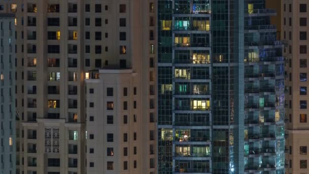 Fenêtres lumineuses dans un immeuble résidentiel en verre moderne à plusieurs étages s'illuminent la nuit timelapse . — Video