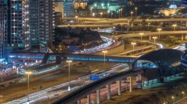 Futuristik binada Dubai metro ve tramvay istasyonu ve lüks gökdelenler arkasında gece timelapse içinde Dubai Marina, Birleşik Arap Emirlikleri. Hava üst görünümden Jlt trafik ile Şeyh zayed yolu üzerinde