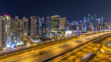 Dubai Yat Limanı timelapse fantastik çatı manzarası. Işıklandırılmış gökdelenler büyük bir şehrin gece, Birleşik Arap Emirlikleri. Havadan görünümden Jlt trafik ile Şeyh zayed yolu üzerinde