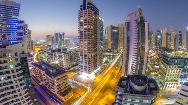 Dubai Yat Limanı hava görünümünü gece geçiş timelapse için bir noktadan günden güneş battıktan sonra. Modern gökdelenler ve konut kuleleri de akşam aydınlatılmış. Köprüde trafik