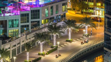 Dubai Marina havadan görünümden bir noktadan gece timelapse. Waterfront adlı mesire üzerinde yürüyen insanlar. Modern gökdelenler ve konut kuleleri parlayan pencerelerle aydınlatılmış
