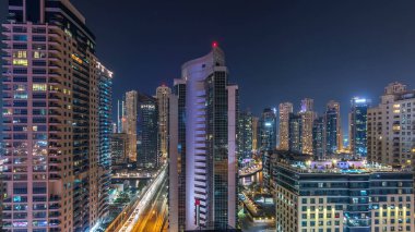 Dubai Marina havadan görünümden bir noktadan gece timelapse. Modern gökdelenler ve konut kuleleri parlayan windows ile aydınlatılmış. Yolda trafik