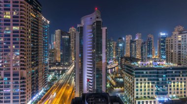 Dubai Marina havadan görünümden bir noktadan gece timelapse. Modern gökdelenler ve konut kuleleri parlayan windows ile aydınlatılmış. Yolda trafik